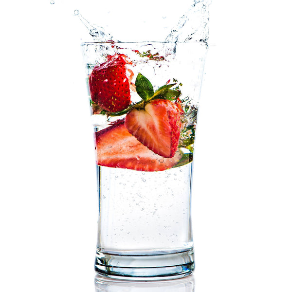 A glass of Strawberry Hard Seltzer with strawberries.