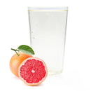 Chilled glass of grapefruit Ranch Water with whole and halved pink grapefruit and green leaf.