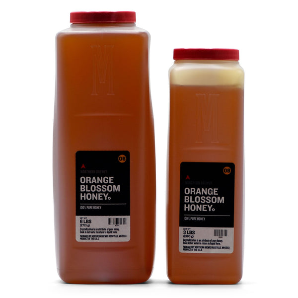 Two bottles of orange blossom honey with red lids on a white background
