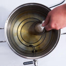 Top-down view of someone adding a bag of grain to a water-filled Gigawort brew kettle